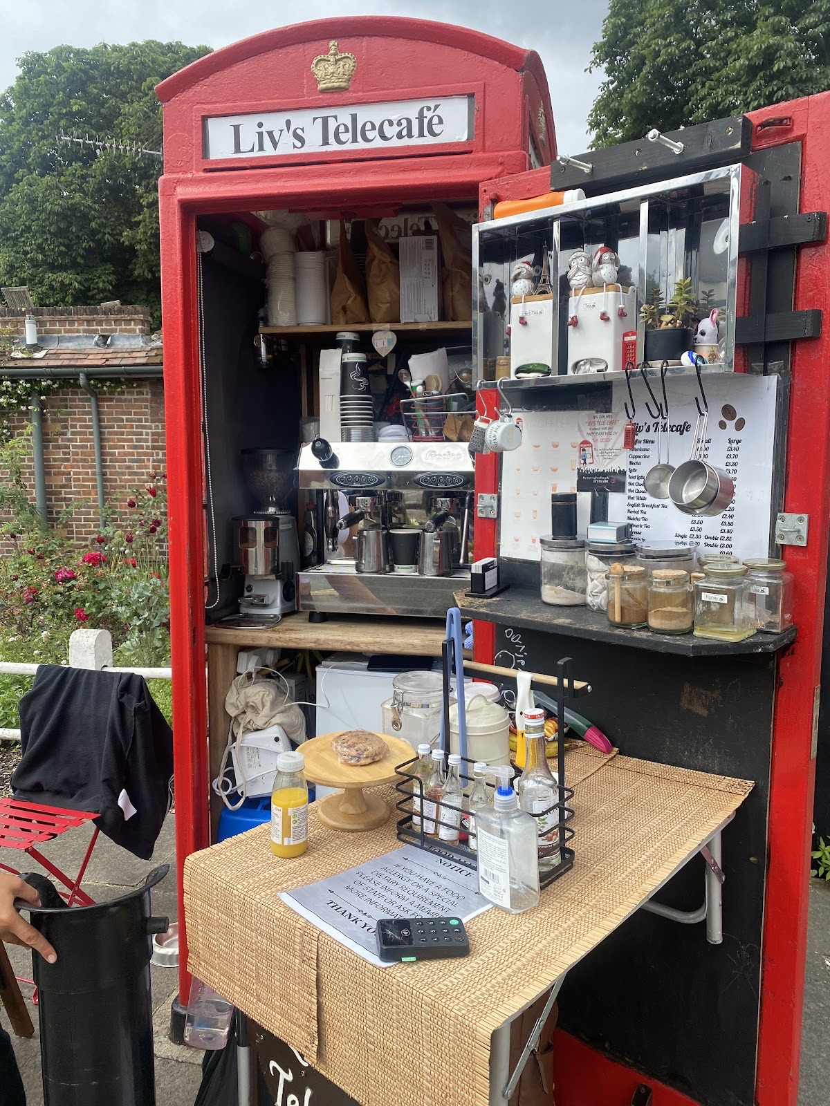 The red phone box kiosk open for service with the espresso machine and syrups inside